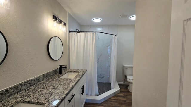 bathroom featuring a shower stall, visible vents, toilet, wood finished floors, and vanity