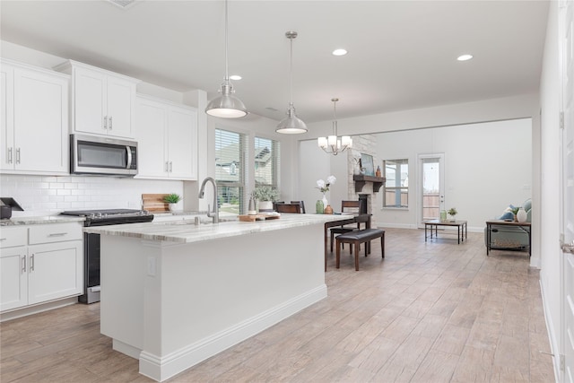 564 Embargo Dr, Fate, TX 75189 - kitchen with light wood-style flooring, a wealth of natural light, appliances with stainless steel finishes, and decorative backsplash
