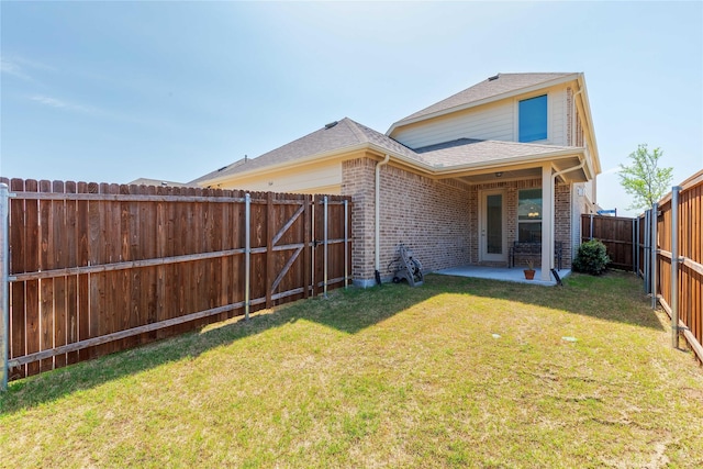 564 Embargo Dr, Fate, TX 75189 - rear view of house with a fenced backyard, brick siding, a patio area, a lawn, and a shingled roof