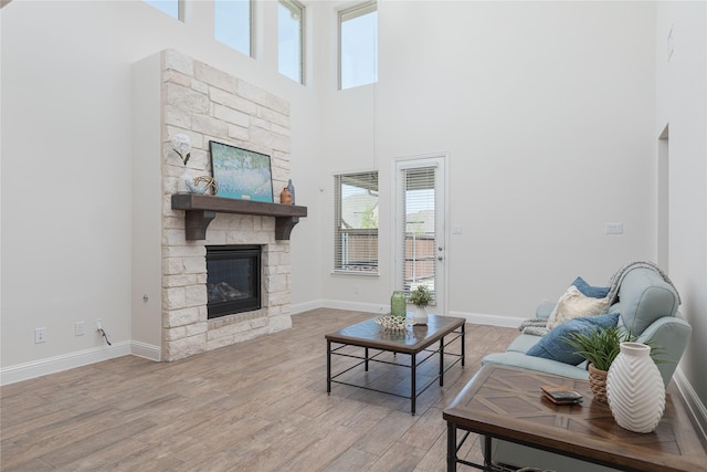 564 Embargo Dr, Fate, TX 75189 - living room with baseboards, a high ceiling, light wood finished floors, and a fireplace
