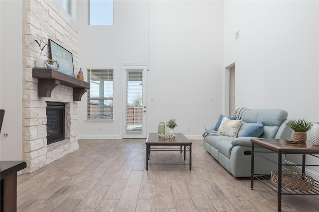 564 Embargo Dr, Fate, TX 75189 - living room with baseboards, a high ceiling, light wood-style flooring, and a fireplace