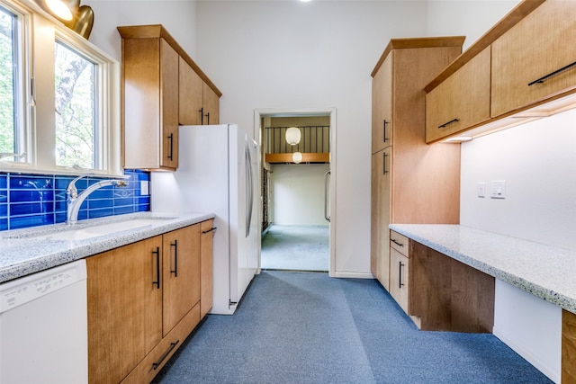 kitchen with light stone counters, light carpet, a sink, white appliances, and decorative backsplash