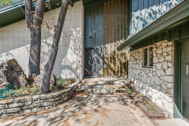 view of exterior entry featuring board and batten siding and stone siding