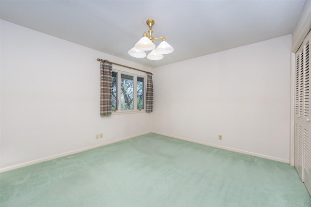 empty room with carpet floors, baseboards, and an inviting chandelier