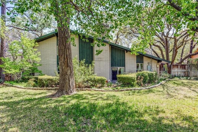 exterior space with a lawn, brick siding, and fence