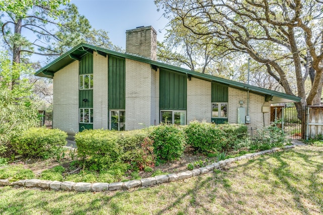 view of home's exterior with brick siding, fence, and a chimney