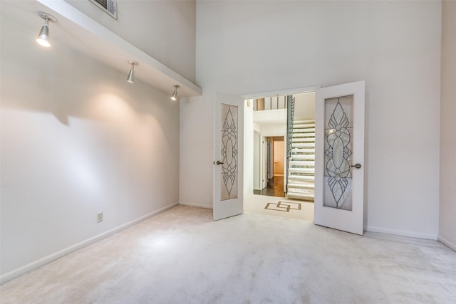 interior space with baseboards, carpet, a towering ceiling, and visible vents