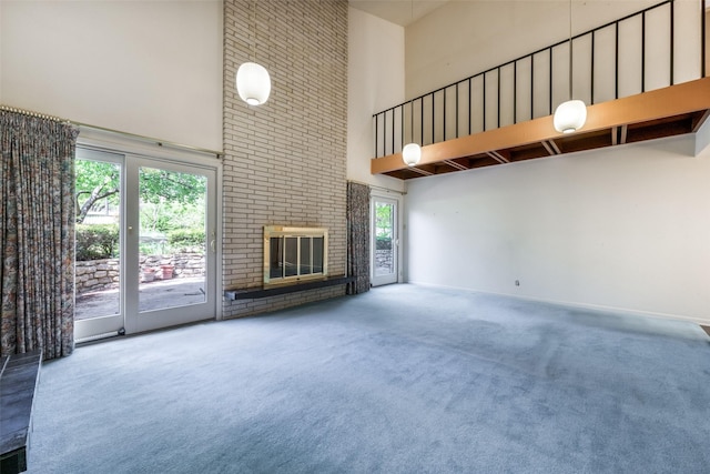 unfurnished living room featuring carpet flooring, a towering ceiling, and a healthy amount of sunlight