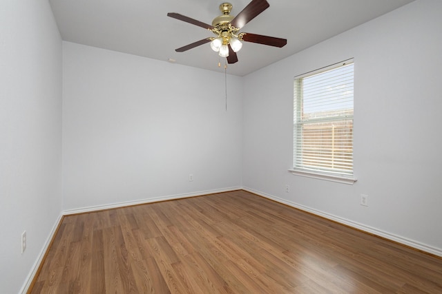 unfurnished room with wood finished floors, a ceiling fan, and baseboards