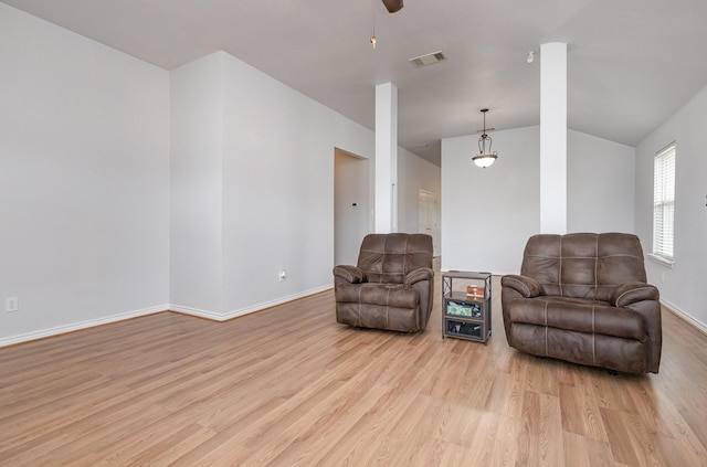 sitting room featuring light wood-style floors, visible vents, vaulted ceiling, and baseboards
