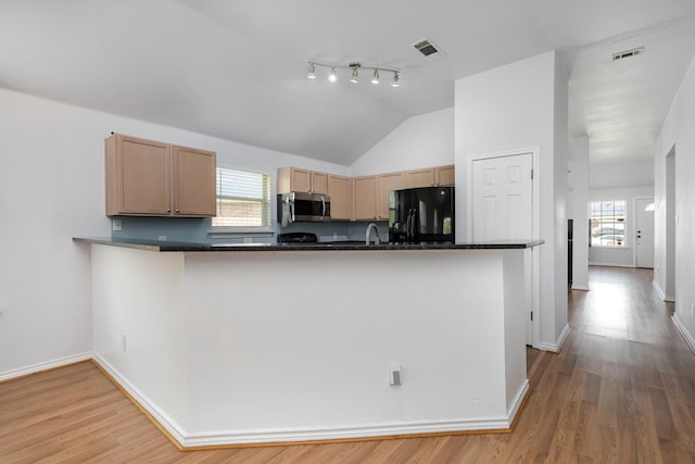 kitchen with stainless steel microwave, dark countertops, light wood finished floors, black refrigerator with ice dispenser, and visible vents