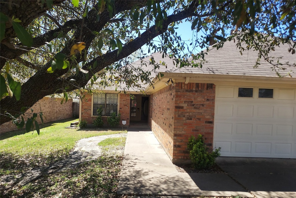 ranch-style house featuring brick siding, a garage, and a front lawn