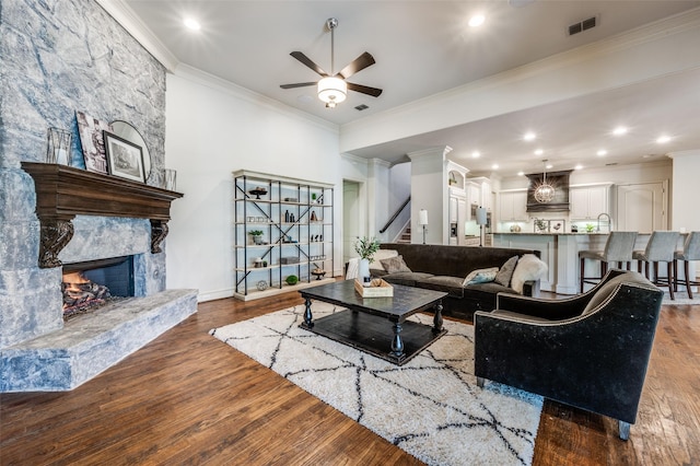 7201 Millard Pond Dr, Mckinney, TX 75071 - living area with crown molding, a ceiling fan, wood finished floors, a stone fireplace, and stairs