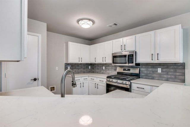 kitchen featuring visible vents, decorative backsplash, light stone countertops, white cabinetry, and appliances with stainless steel finishes