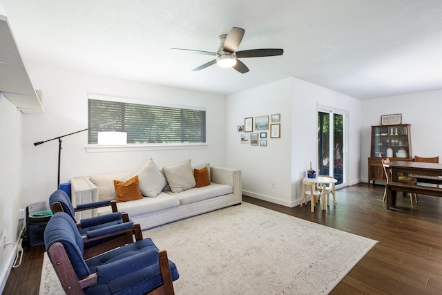 living area featuring baseboards, a wealth of natural light, ceiling fan, and dark wood-style flooring