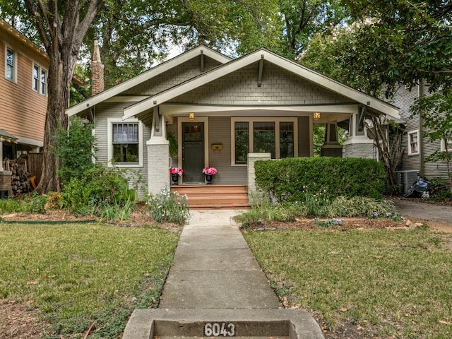 view of front of home featuring a chimney, central AC unit, a porch, and a front yard