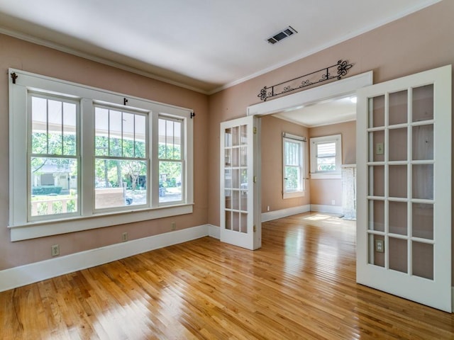 empty room featuring light wood-type flooring, visible vents, french doors, and crown molding