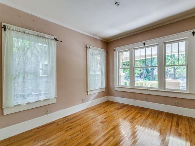 spare room with baseboards, wood finished floors, and ornamental molding