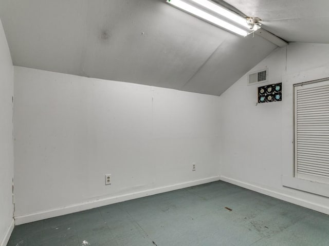 additional living space featuring baseboards, lofted ceiling, and visible vents