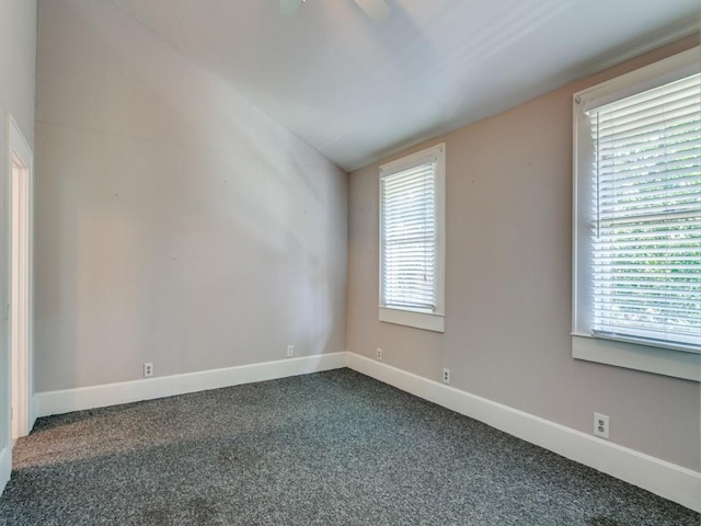 spare room with baseboards, lofted ceiling, and dark carpet