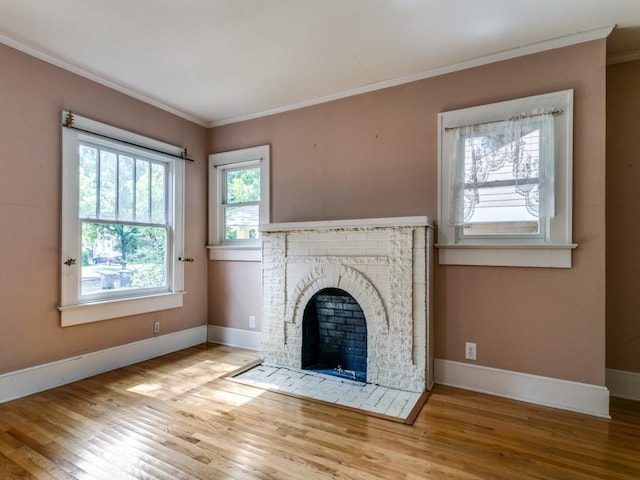 unfurnished living room featuring baseboards, a fireplace, crown molding, and wood finished floors
