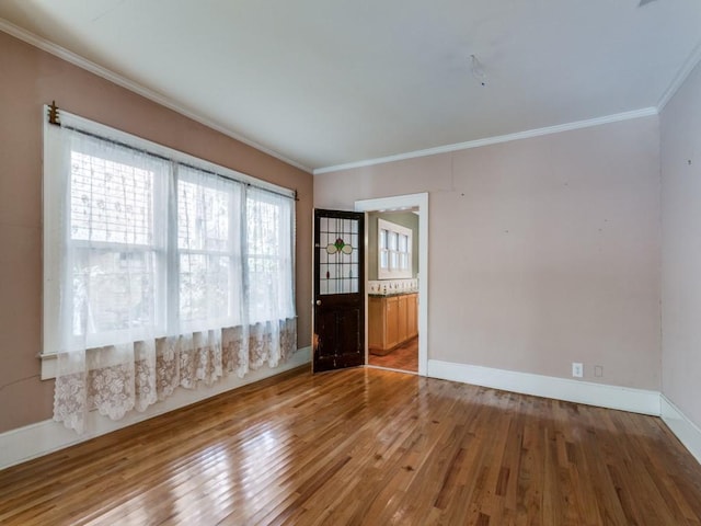 unfurnished room with hardwood / wood-style floors, ornamental molding, and baseboards