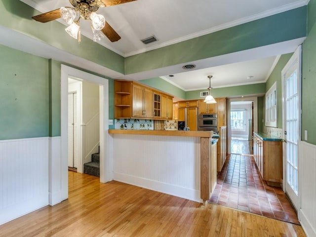 kitchen featuring light wood-style flooring, oven, paneled built in fridge, open shelves, and wainscoting
