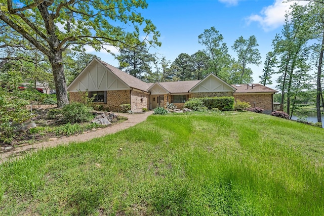single story home featuring brick siding, a front lawn, a garage, and roof with shingles