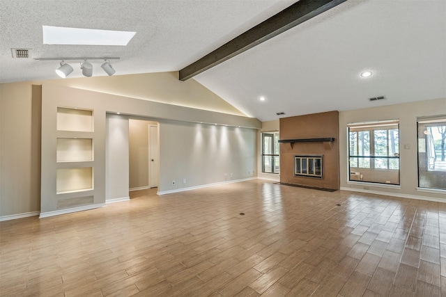 unfurnished living room featuring light wood-type flooring, visible vents, a textured ceiling, and a large fireplace