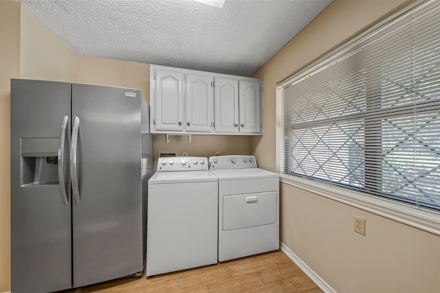 laundry area with light wood-style floors, independent washer and dryer, a textured ceiling, baseboards, and cabinet space