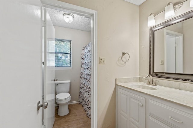 bathroom featuring baseboards, toilet, a textured ceiling, vanity, and wood finished floors