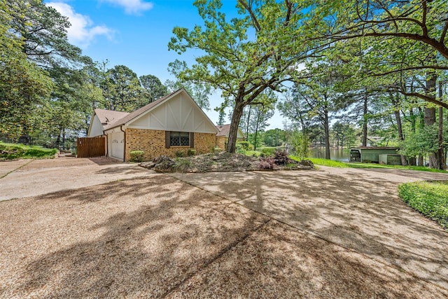 view of side of property with brick siding, an attached garage, and concrete driveway
