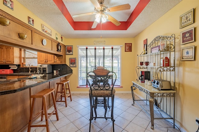1511 Dolly Ln, Hideaway, TX 75771 - dining room with a textured ceiling, light tile patterned floors, ceiling fan, a tray ceiling, and baseboards