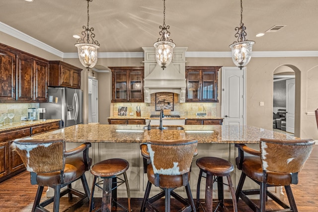 kitchen with arched walkways, stainless steel refrigerator with ice dispenser, crown molding, and dark wood finished floors