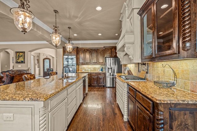 kitchen with ornamental molding, stainless steel appliances, arched walkways, glass insert cabinets, and a sink