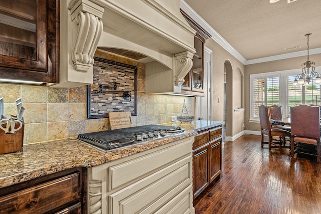 kitchen featuring stainless steel gas cooktop, ornamental molding, arched walkways, dark wood-type flooring, and custom range hood