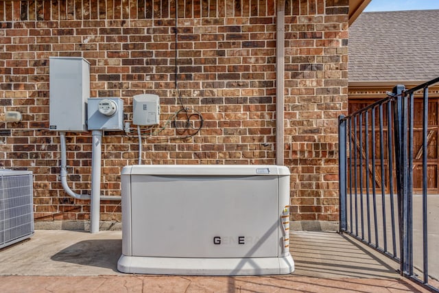 exterior details with electric meter, a power unit, brick siding, and central AC