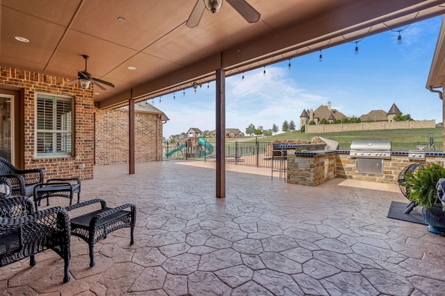 view of patio with exterior kitchen, fence, area for grilling, and a playground