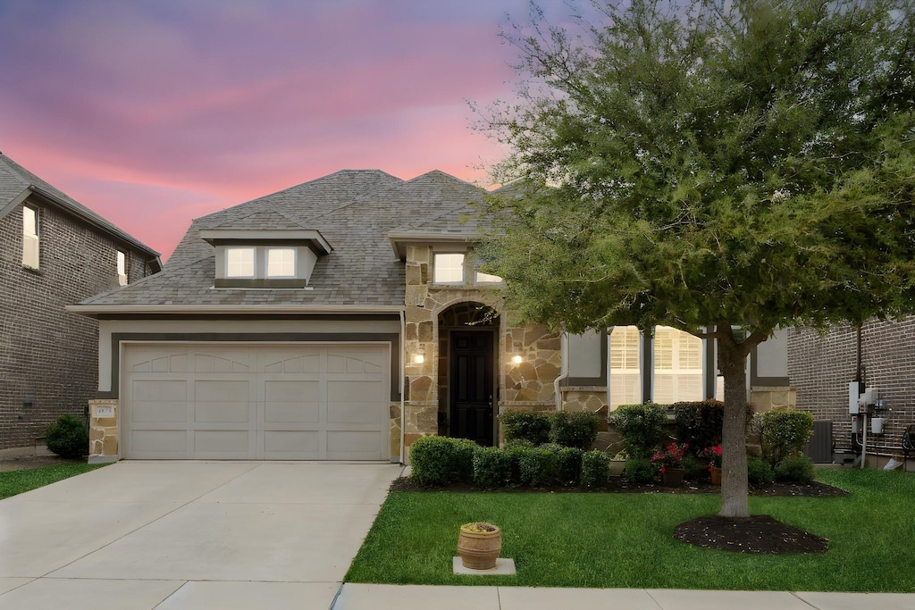 6413 Whiskerbrush Rd, Flower Mound, TX 76226 - french provincial home featuring stone siding, a garage, central AC, a front lawn, and driveway
