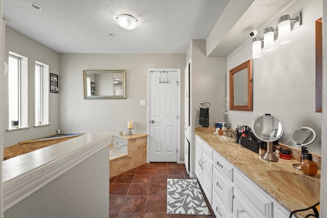 bathroom with a sink, double vanity, and a textured ceiling