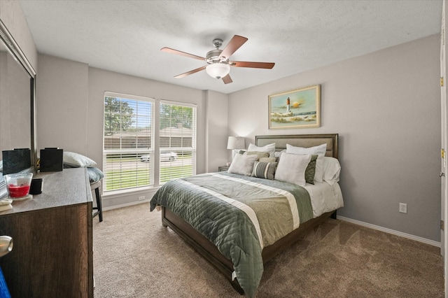 bedroom featuring light carpet, baseboards, a ceiling fan, and a textured ceiling