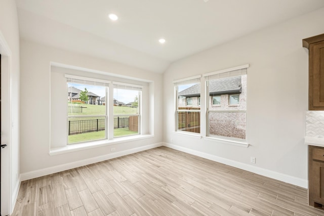 unfurnished dining area featuring baseboards, light wood-type flooring, recessed lighting, and vaulted ceiling