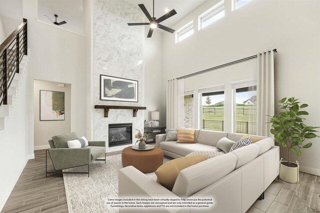 living room with a high ceiling, plenty of natural light, baseboards, a premium fireplace, and ceiling fan
