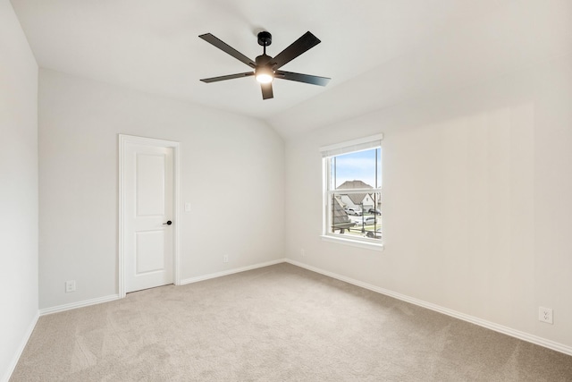 spare room featuring light carpet, ceiling fan, baseboards, and vaulted ceiling
