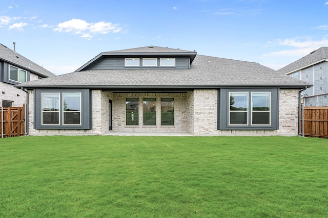 rear view of property featuring a shingled roof, a patio, and brick siding