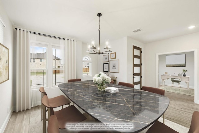 dining area featuring a chandelier, light wood finished floors, and baseboards