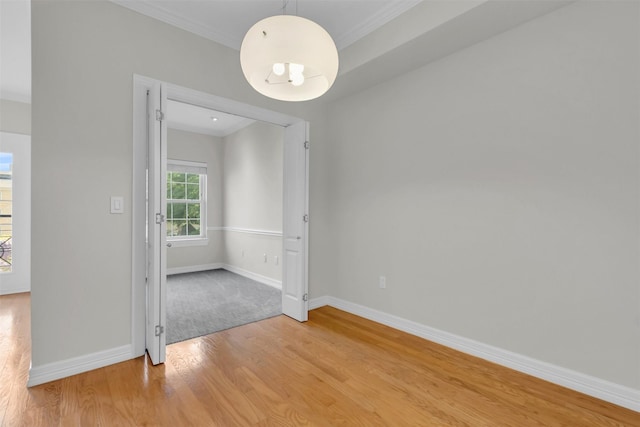 unfurnished room featuring baseboards, crown molding, light wood-style flooring, and a chandelier
