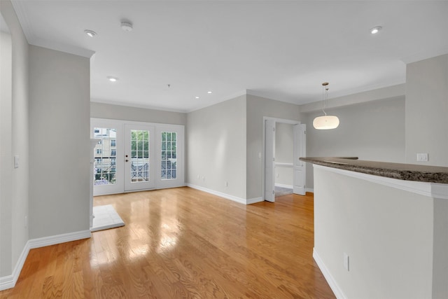 unfurnished living room with light wood finished floors, baseboards, ornamental molding, recessed lighting, and french doors