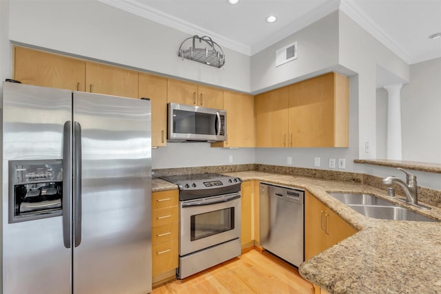 kitchen featuring visible vents, crown molding, appliances with stainless steel finishes, a sink, and light stone counters