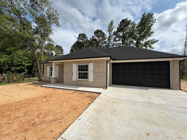 ranch-style home featuring roof with shingles, a garage, brick siding, fence, and concrete driveway